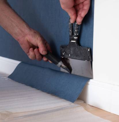 Man cutting wallpaper. Maintenance repair works renovation in the flat. Man cutting wallpaper. Maintenance repair works renovation in the flat. Restoration indoors.